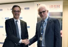 Deux hommes de l'Ineris et de l'IRSN renforcent leur partenariat en se serrant la main devant une banderole.