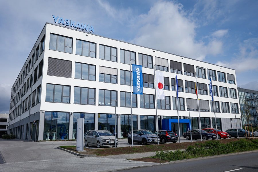 Yaskawa inaugure son nouveau siège européen, avec des voitures garées devant le bâtiment.