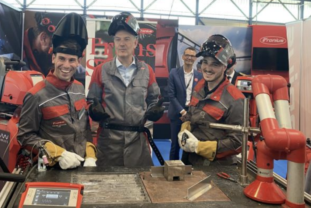Trois hommes posent devant une machine au Championnat de France de soudure.