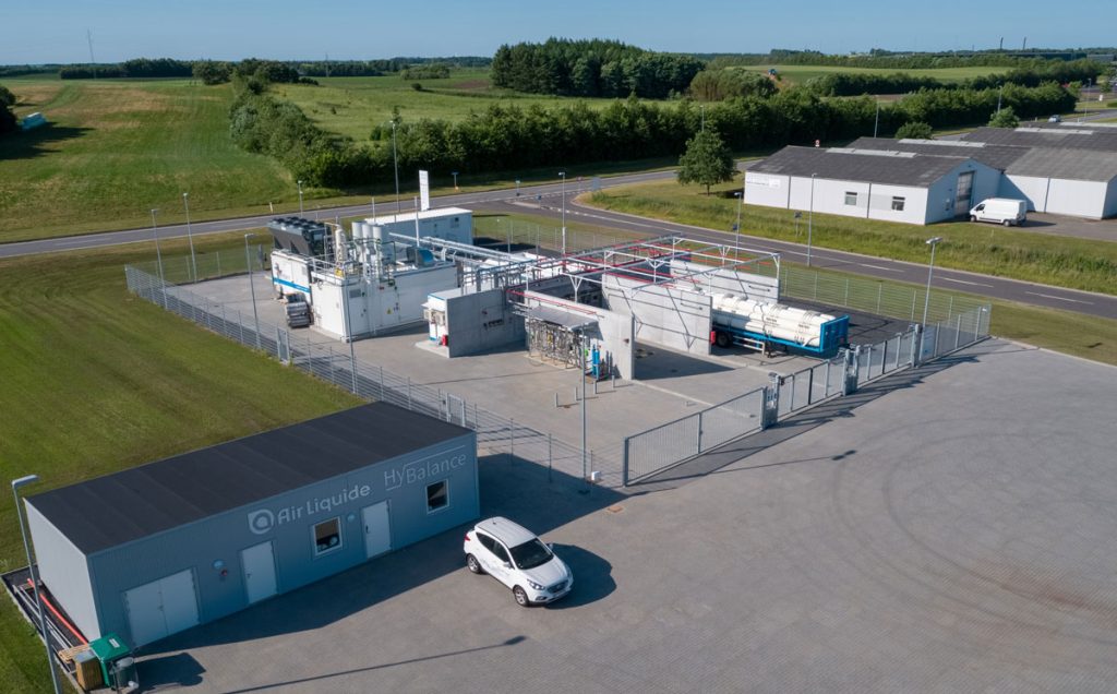 Une vue aérienne d'une station-service avec une voiture garée devant, présentant de nouveaux défis et impliquant les acteurs du domaine de l'hydrogène.
