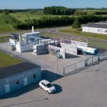 Une vue aérienne d'une station-service avec une voiture garée devant, présentant de nouveaux défis et impliquant les acteurs du domaine de l'hydrogène.