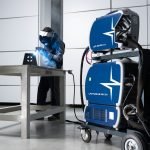 Un homme satisfait travaillant avec facilité d'utilisation d'une machine à souder dans une pièce.