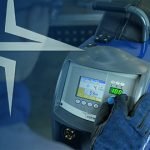 Un homme tient une machine à souder devant un écran bleu, garantissant une facilité d'utilisation pour une satisfaction maximale des soudeurs.