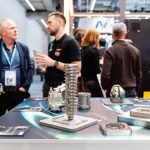 Un groupe de personnes debout autour d’une table lors d’un salon professionnel.