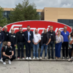 Un groupe de personnes posant devant une pancarte.