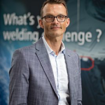 Un homme en costume debout devant une banderole.