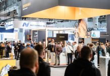 Les participants se rassemblent et réseautent dans un salon très fréquenté à Formnext 2024, avec divers stands d'entreprises exposés.