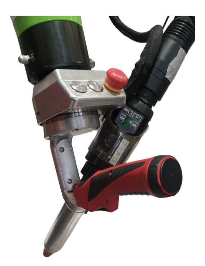Gros plan d'un outil de soudage plastique portatif avec une poignée rouge et plusieurs boutons de commande. L'appareil semble avoir une buse pour chauffer et appliquer des matériaux, ainsi qu'un composant vert et noir fixé en haut.