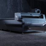 Une grande machine industrielle à l'aspect métallique et épuré se dresse dans une pièce faiblement éclairée. Avec son tuyau d'aération proéminent et ses solutions de découpe de pointe, la machine est encadrée par des murs texturés et sombres.