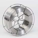 Une grande bobine de fil métallique est enroulée étroitement dans un cadre métallique circulaire. Le fil lisse et brillant suggère qu'il pourrait être utilisé à des fins de soudage, même sur les chantiers navals. Le fond blanc met en valeur la texture métallique.