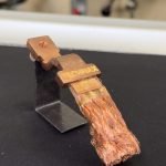 Une borne électrique en cuivre, dotée de fils de cuivre tressés à une extrémité, est montée sur un support métallique. Le connecteur, étiqueté « TECHMAX », semble faire partie d'une installation industrielle utilisant la technologie laser pour plus de précision et de fiabilité.