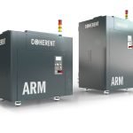 Deux grandes machines industrielles, baptisées « ARM » et « COHERENT », sont placées côte à côte. Chacune est équipée d'un panneau de commande, de voyants d'avertissement sur le dessus et d'une enveloppe métallique conçue pour les applications laser de procédé. Le fond est uni et blanc.