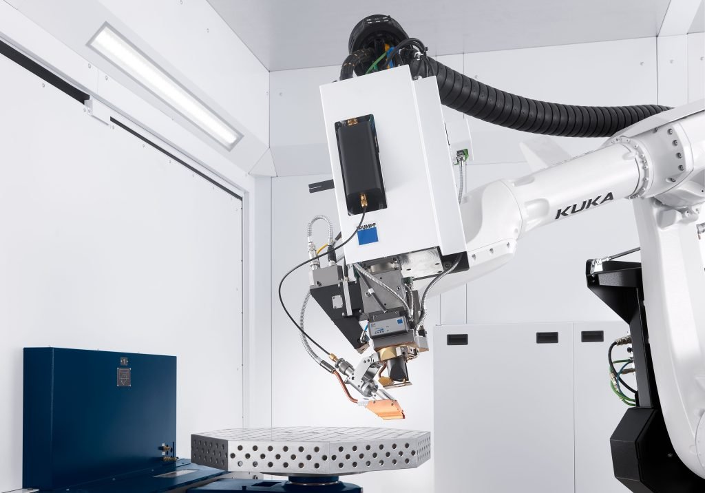 Un bras robotique industriel blanc avec câblage et composants métalliques est positionné sur une plate-forme métallique perforée, mettant en évidence le laser d'utilisation dans une pièce propre et bien éclairée avec des murs blancs.
