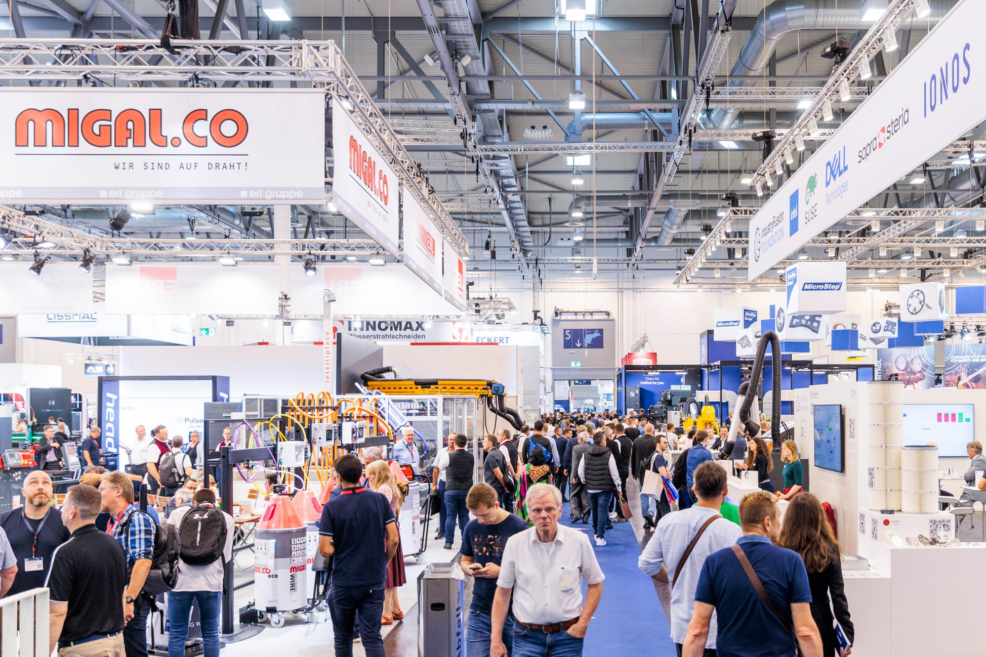 Le sol d'un salon professionnel est occupé par de nombreux stands, bannières et présentoirs. Parmi la foule qui explore les expositions sous les lumières vives du grand hall de convention, des produits innovants comme Brouillon auto attirent l'attention des participants.