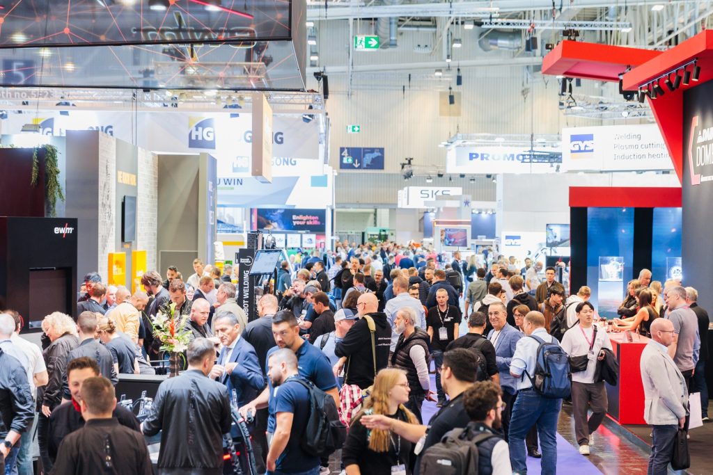 Une foule nombreuse se rassemble autour des stands du salon Schweissen & Schneiden, très fréquenté, pour découvrir les innovations dans un hall d'exposition spacieux et bien éclairé. Diverses enseignes et présentations d'entreprises laissent entrevoir ce qui se passera lors de l'édition 2025.