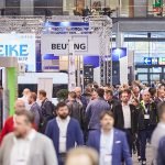 Une foule nombreuse traverse un hall d'exposition de tôlerie très fréquenté à l'EuroBLECH 2026, avec divers stands et bannières d'entreprises visibles, dont une étiquetée "BEUTING". L'atmosphère semble animée et professionnelle.