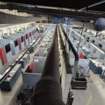 Vue grand angle d'un atelier industriel comportant plusieurs postes de travail divisés par des cloisons ; chaque poste est équipé de matériel et d'outils, et des plafonniers éclairent la zone.