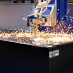 Une machine de découpe au plasma CNC découpe une feuille de métal, produisant des étincelles brillantes lorsque l'arc de plasma à haute température se déplace le long de la surface du matériau.