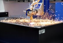 Une machine de découpe au plasma CNC découpe une feuille de métal, produisant des étincelles brillantes lorsque l'arc de plasma à haute température se déplace le long de la surface du matériau.