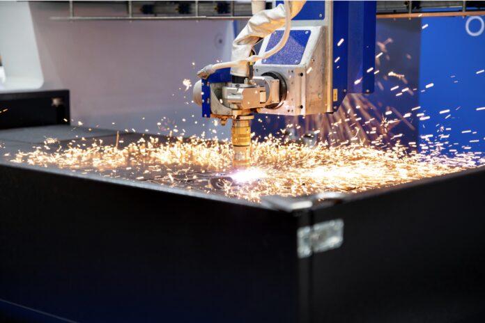 Une machine de découpe au plasma CNC découpe une feuille de métal, produisant des étincelles brillantes lorsque l'arc de plasma à haute température se déplace le long de la surface du matériau.