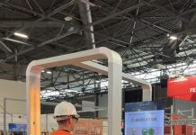 JO-Safe : le portique de détection instantanée des EPI Une personne portant un équipement de protection individuelle (EPI) — un casque de chantier blanc et un gilet de sécurité orange — se tient debout dans un portique de détection JO-Safe, face à un écran qui affiche son image ainsi que le message « Accès refusé » accompagné d’une croix rouge, indiquant que l’accès lui est refusé.