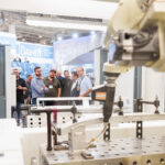 Un groupe de personnes observe un bras robotique industriel dans un environnement d'usine.