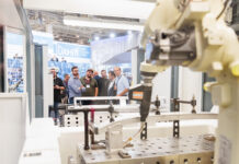 Schweissen Schneiden 2029 : plus de 85 % des surfaces déjà réservées Un groupe de personnes observe un bras robotique industriel dans un environnement d'usine.