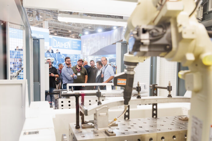 Un groupe de personnes observe un bras robotique industriel dans un environnement d'usine.